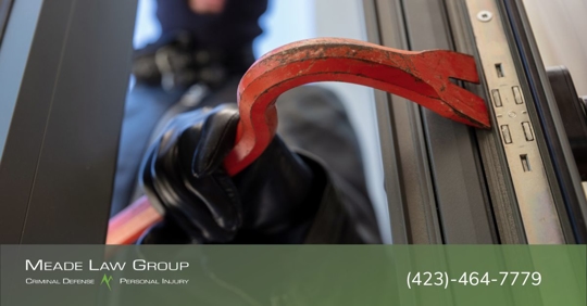 Man using a crowbar to break into a home.